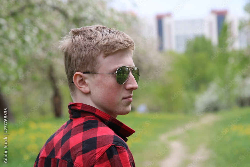 Boy in the red shirt at the city park, summer day, natural lighting.