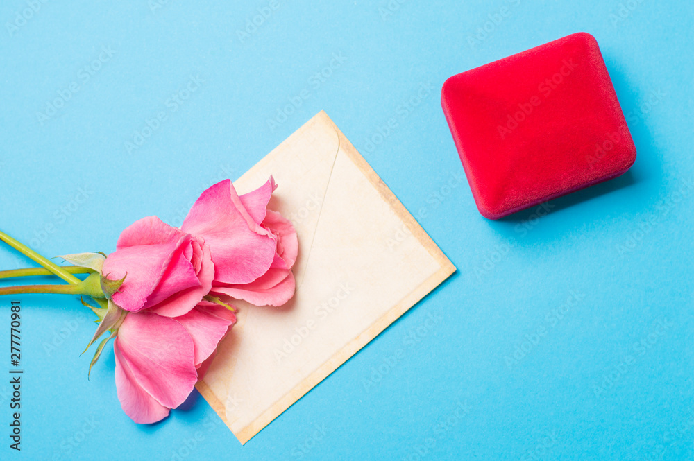 ring in a box with an envelope and roses on a blue background ring in a box with an envelope and roses on a blue background