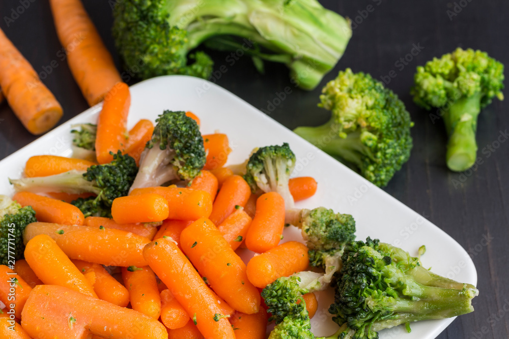 Vegetable salad: broccoli and carrots in a white plate on a black background. Vegetable salad: broccoli and carrots in a white plate on a black background.