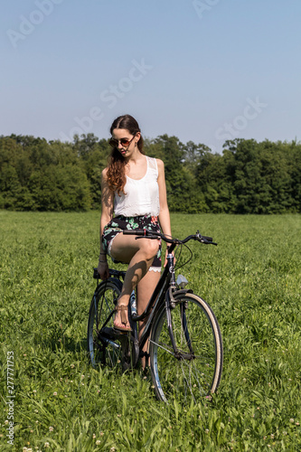 Ragazza in sella alla sua bicicletta in una giornata di sole al parco