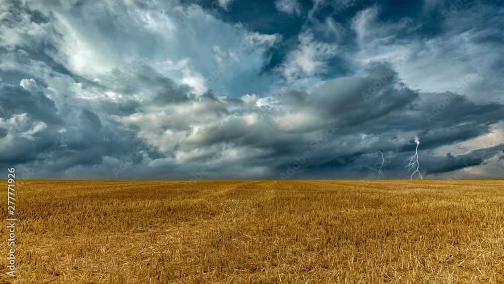 abgemähtes Getreidefeld vor dramatischem Himmel mit Gewitter abgemähtes Getreidefeld vor dramatischem Himmel mit Gewitter