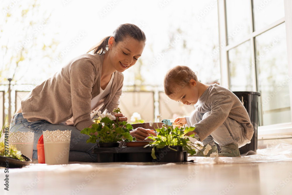 Mother and daughter planting flowers together on balcony Mother and daughter planting flowers together on balcony