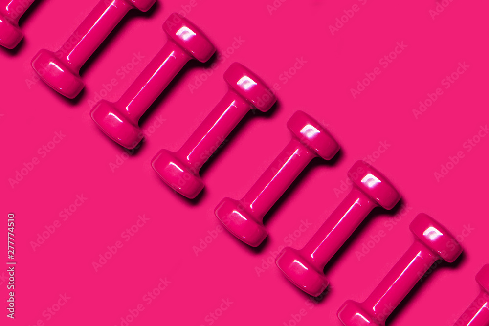 Row of pink dumbbells on pink background. Health care concept. Row of pink dumbbells on pink background. Health care concept.