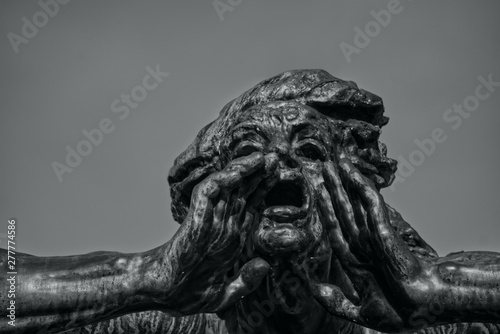 Statue with a gesture of call. Head of sculpture with open mouth and hands. Background of pure sky. Black and white photo.