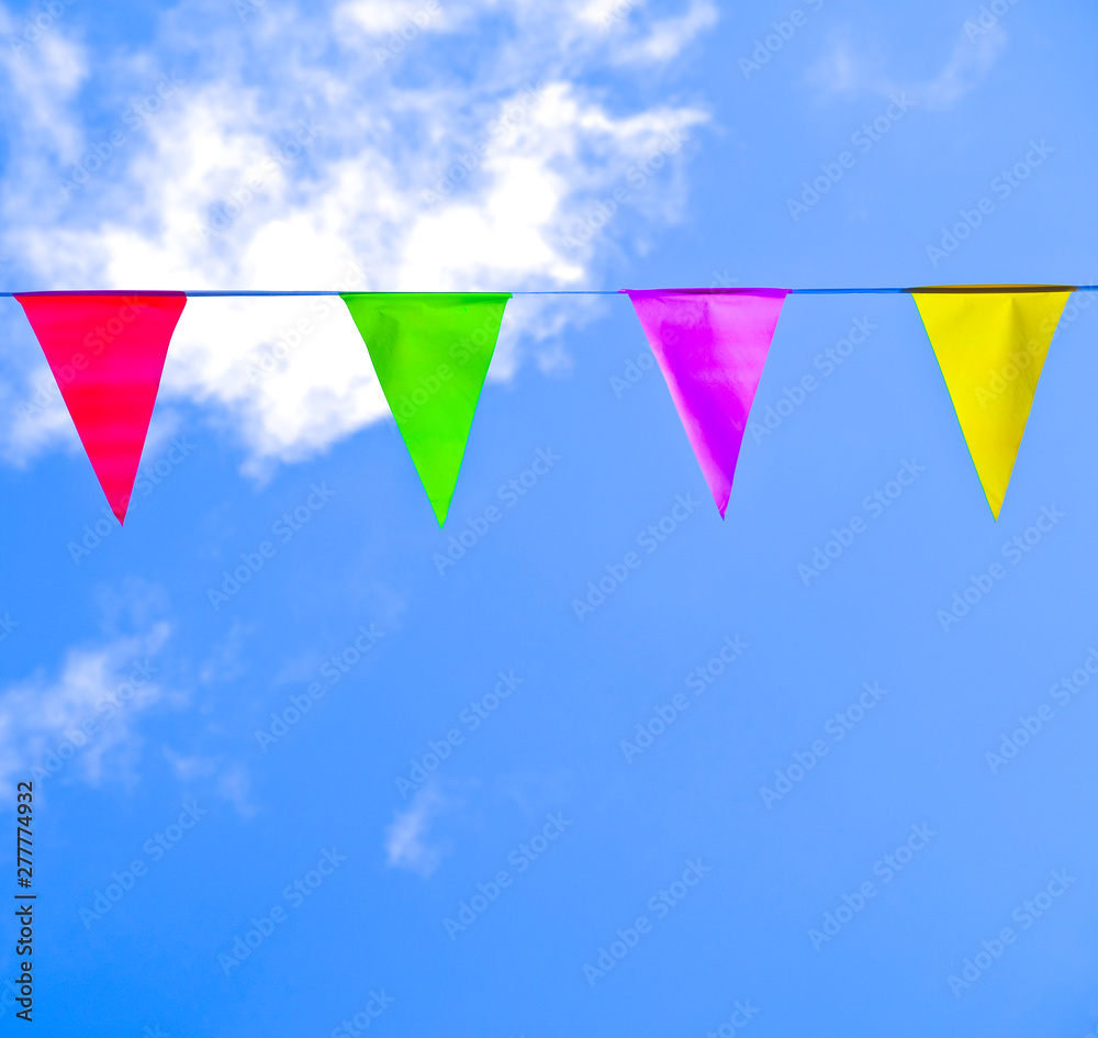 Bright colorful triangle flags on a string, blue sky with white fluffy clouds. Bright colorful triangle flags on a string, blue sky with white fluffy clouds.