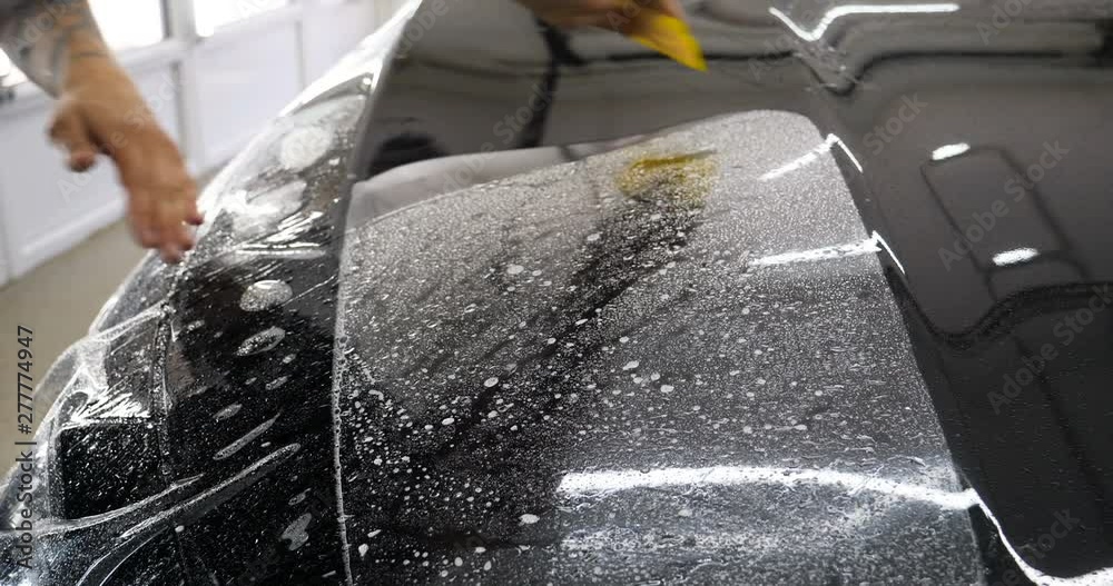 Close up to PPF installation process on a front headlight and hood. PPF