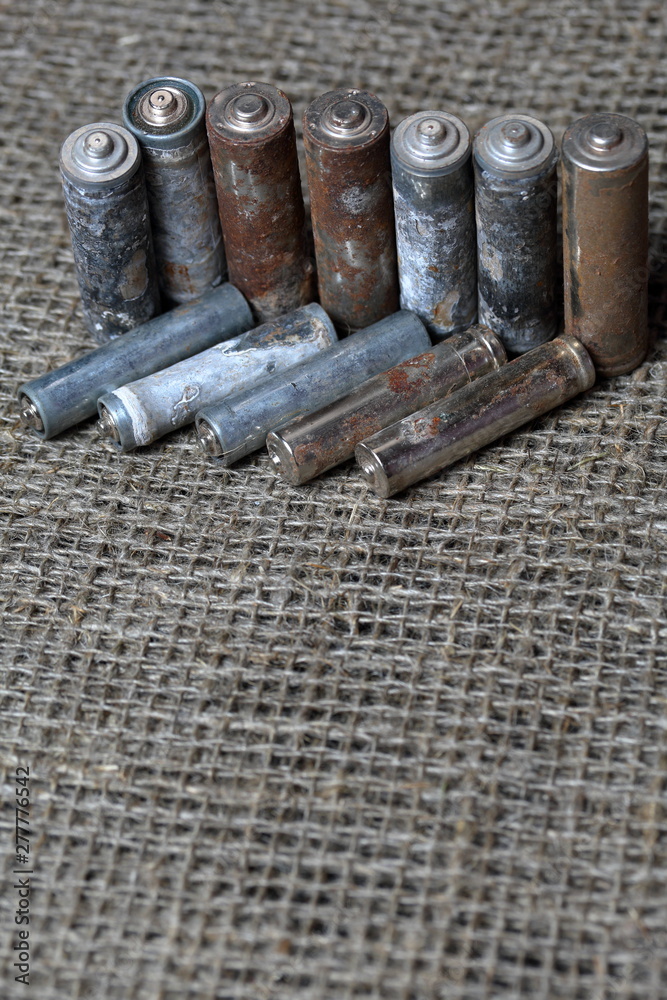 Spent batteries lie on a rough linen background. Covered with corrosion. Recycling and environmental protection. Spent batteries lie on a rough linen background. Covered with corrosion. Recycling and environmental protection.