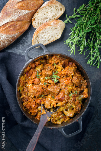 Traditional Polish kraut stew bigos with sausage, meat and mushrooms as top view in a cast iron pot on an old wooden table photo