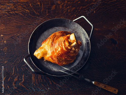Crispy roasted pork knuckle in a pan on wooden table photo