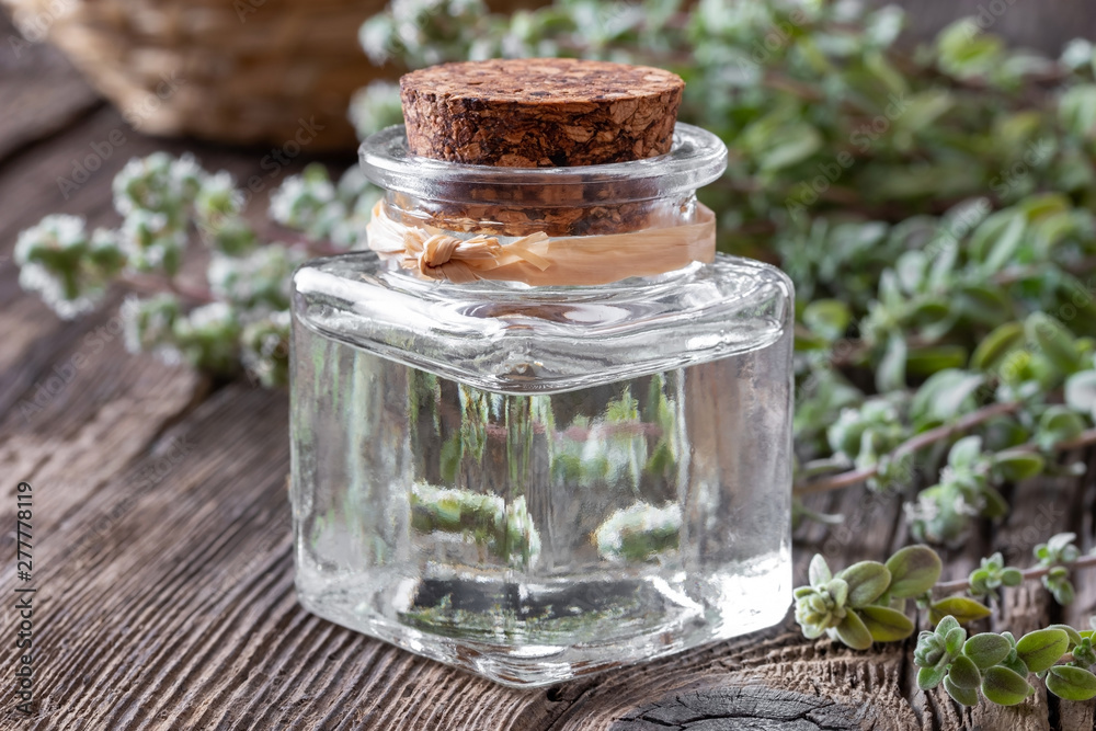 A bottle of marjoram essential oil with marjoram A bottle of marjoram essential oil with marjoram