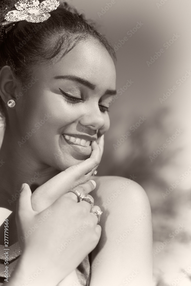 Portrait of young confident woman smiling. Eyes closed and hands on face. Beautiful make up look. Black and white photograph.