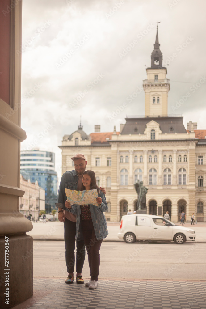 two young people, friends or couple, looking at a city map together. Old European city square architecture.