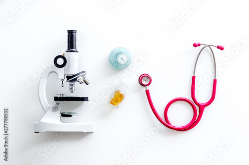 Medical tests on work table of doctor with microscope, stethoscope, test tube, pills on white background top view