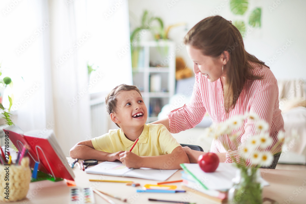 mother helps son to do lessons. home schooling, home lessons. the tutor is engaged with the child, teaches to write and count. out-of-school lessons with a teacher. mother helps son to do lessons. home schooling, home lessons. the tutor is engaged with the child, teaches to write and count. out-of-school lessons with a teacher.