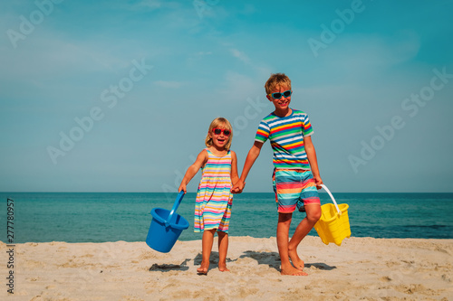 happy cute boy and girl play with sand on beach photo