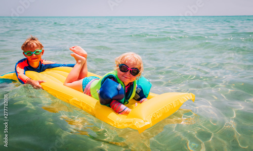 happy boy and girl swim on inflatable mattress in sea