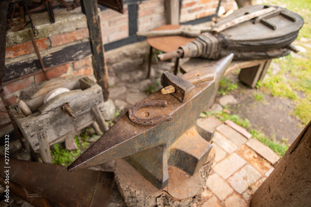 Tools in an old blacksmith's workshop. Horseshoe and hammer on a large anvil.