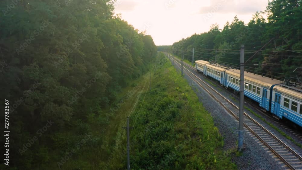 Aerial view of the suburban train (commuter rail) moving through the spring forest Aerial view of the suburban train (commuter rail) moving through the spring forest
