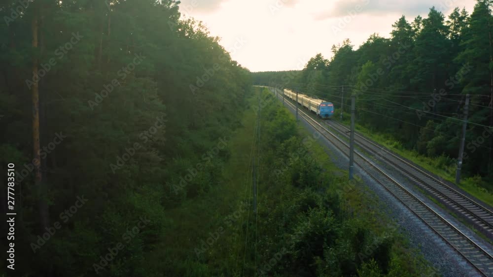 Aerial view of the suburban train (commuter rail) moving through the spring forest Aerial view of the suburban train (commuter rail) moving through the spring forest