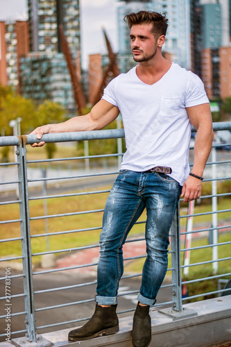 Handsome fit man in white t-shirt outdoor in city setting, looking away © theartofphoto
