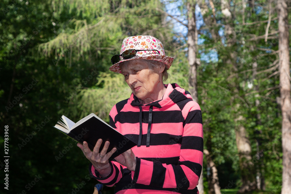 Portrait of elderly woman in hat resting after a walk on a park bench in sunlight. Reading book, thinking. Portrait of elderly woman in hat resting after a walk on a park bench in sunlight. Reading book, thinking.