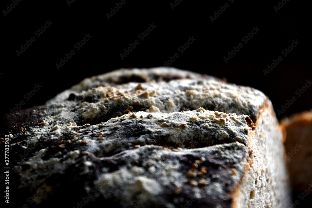 A loaf of bread with sesame cut on a cutting board. A loaf of bread with sesame cut on a cutting board.