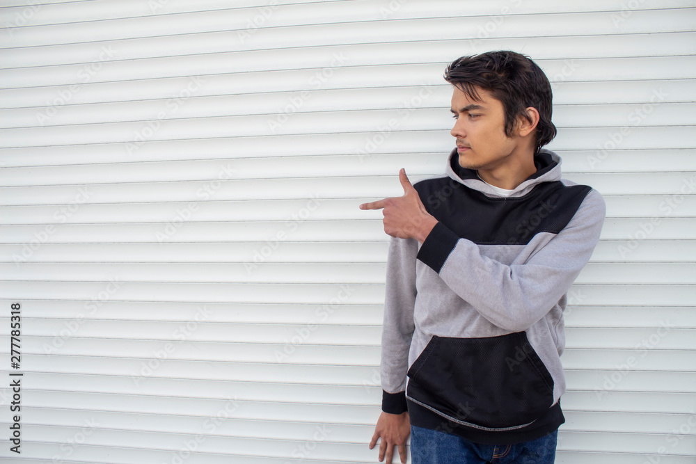 A young guy on a white background shows a finger to the side. A young guy on a white background shows a finger to the side.
