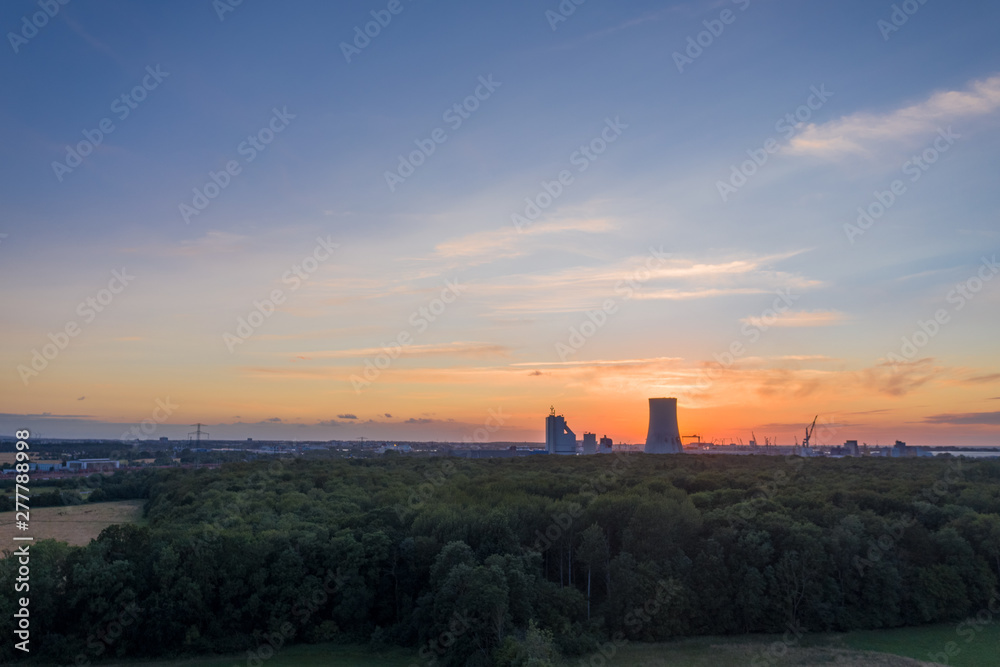 sunset over the city - forest and power plant in the background