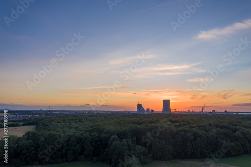 sunset over the city - forest and power plant in the background