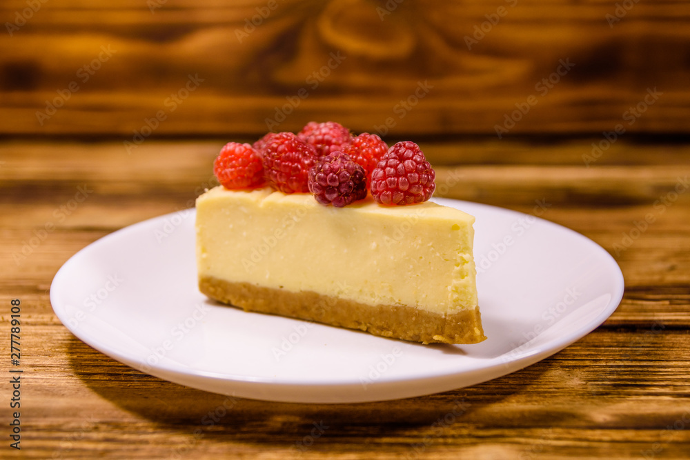 White plate with cheesecake New York and raspberries on wooden table White plate with cheesecake New York and raspberries on wooden table