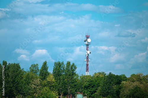 Military communications tower with various communication equipments and antennas for radio and 5G inside a forest