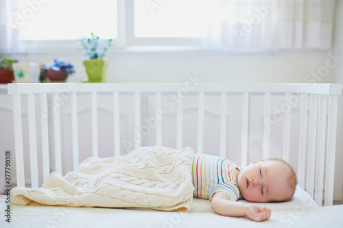 Baby sleeping in co-sleeper crib attached to parents' bed photo
