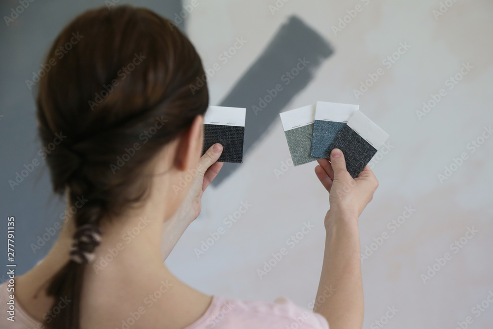 Young woman choosing a perfect shade of grey for walls in her new home Young woman choosing a perfect shade of grey for walls in her new home