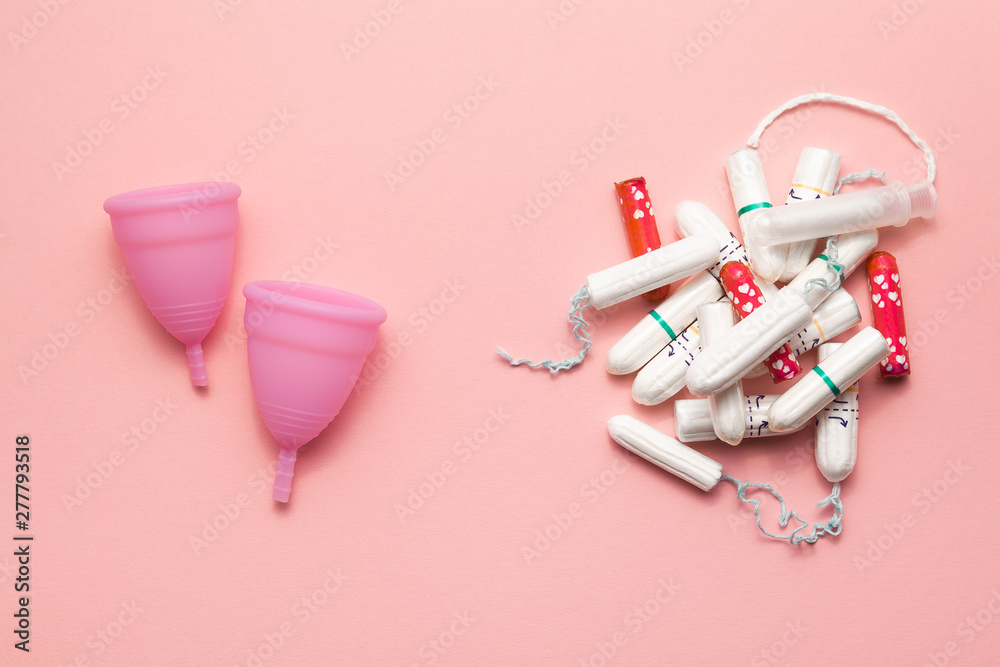 Two reusable silicone menstrual cups and heap of tampons comparison on a soft pink background. Modern female intimate alternative gynecological hygiene. Eco zero waste concept Two reusable silicone menstrual cups and heap of tampons comparison on a soft pink background. Modern female intimate alternative gynecological hygiene. Eco zero waste concept