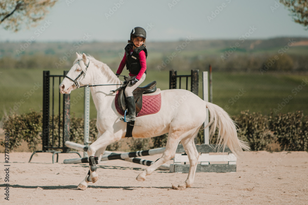 Determined girl jockey on horse riding on racetrack on a sunny day Determined girl jockey on horse riding on racetrack on a sunny day