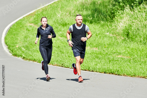 man and woman jogging and running outdoors in park photo