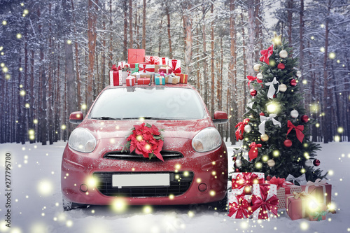 Car with gifts and wreath near Christmas tree in snowy forest on winter day © New Africa