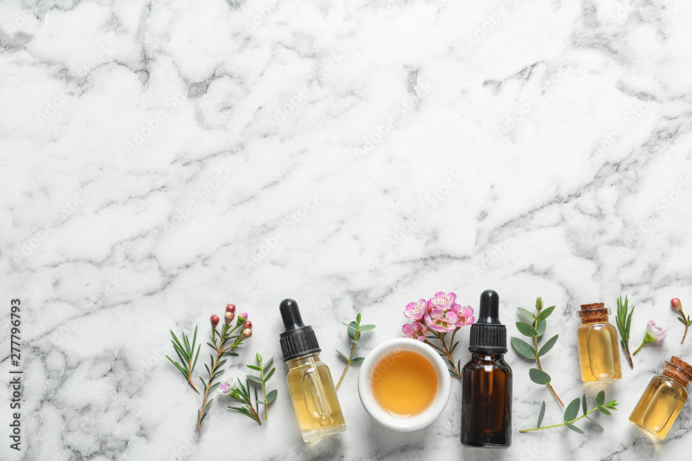 Flat lay composition with bottles of natural tea tree oil and space for text on white marble background Flat lay composition with bottles of natural tea tree oil and space for text on white marble background