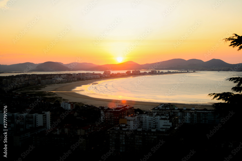 Sunset in a wonderful image of a coastal town, river flowing into a beach bathed by the sunset sun. Laredo, Cantabria, Spain