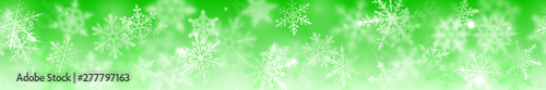 Christmas banner of complex blurred and clear snowflakes in white colors on green background. With horizontal repetition
