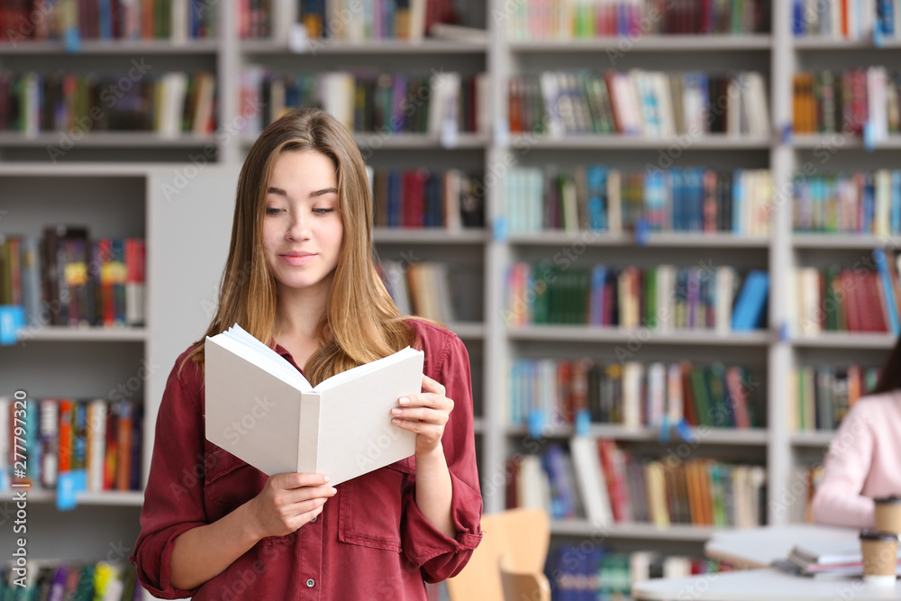 Young pretty woman reading book in library. Space for text Young pretty woman reading book in library. Space for text
