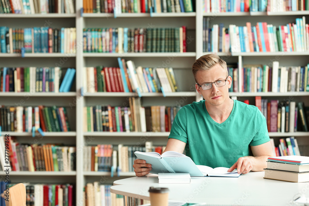 Pensive young man with books at table in library. Space for text Pensive young man with books at table in library. Space for text