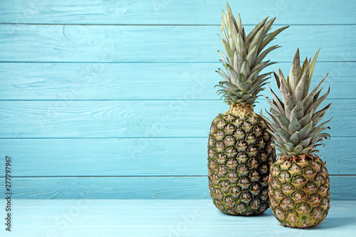 Fresh delicious pineapples on table against wooden background, space for text