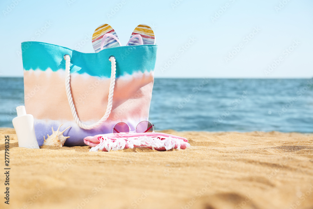 Stylish beach accessories on sand near sea. Space for text Stylish beach accessories on sand near sea. Space for text
