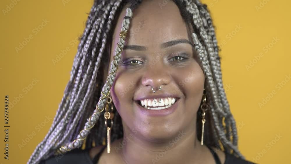 Young beautiful african american girl with an afro dreads hairstyle. Attractive girl. Cute toothy smile. Yellow background. Young beautiful african american girl with an afro dreads hairstyle. Attractive girl. Cute toothy smile. Yellow background.