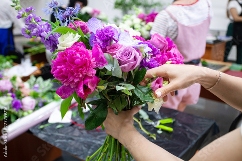 Female florist create a bouquet at workplace. Floristics workshop. Making beautiful flower bouquets and floral decorations..