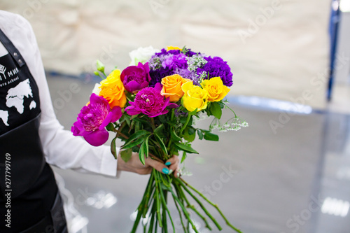 Female florist create a bouquet at workplace. Floristics workshop. Making beautiful flower bouquets and floral decorations..