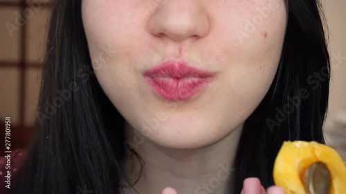 Young brunette woman eats red sweet cherry. Close-up.