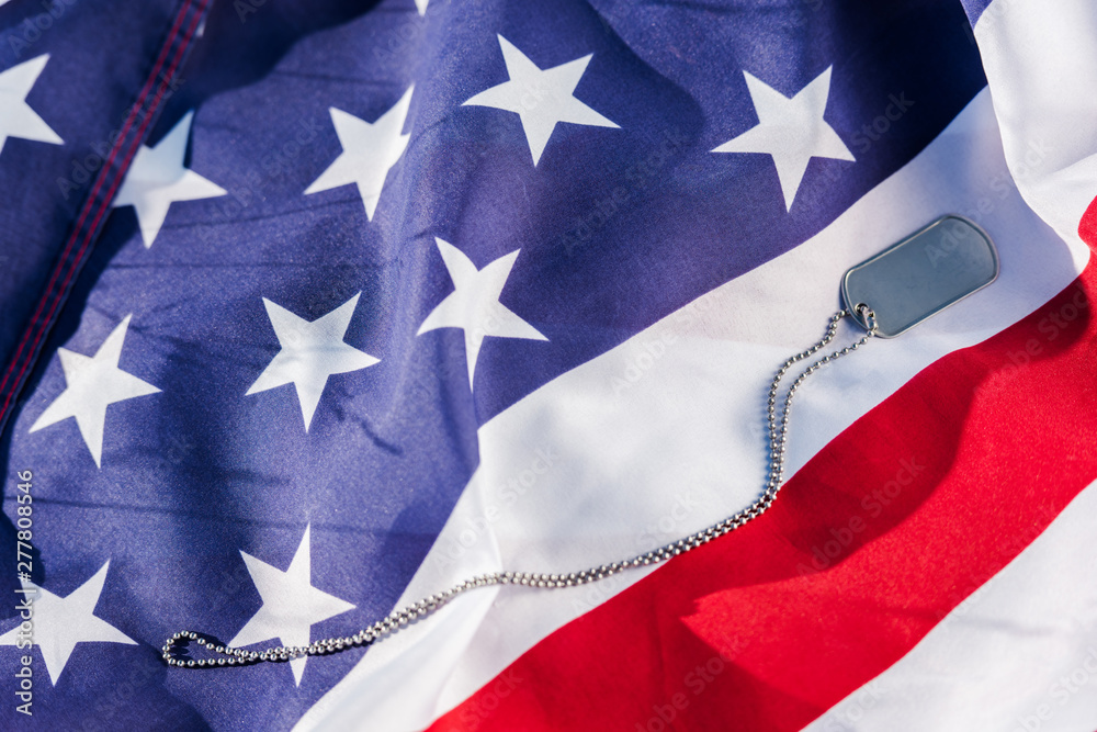 Fototapeta premium Metallic badge on chain near American flag with stars and stripes