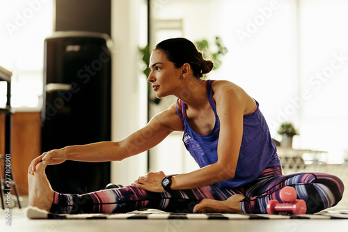 Young female athlete stretching on the floor at home.